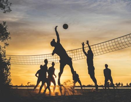people playing beach volleyball at sunset