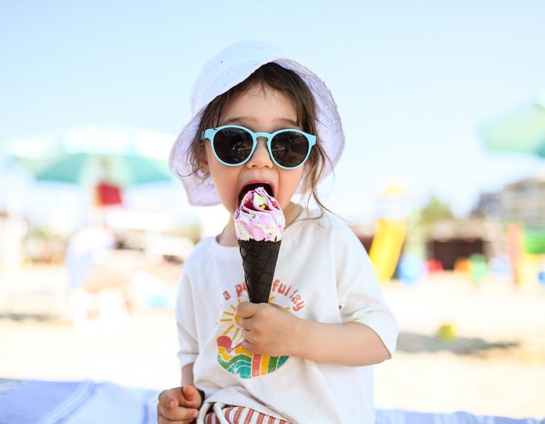 little girl eating ice cream on the beach
